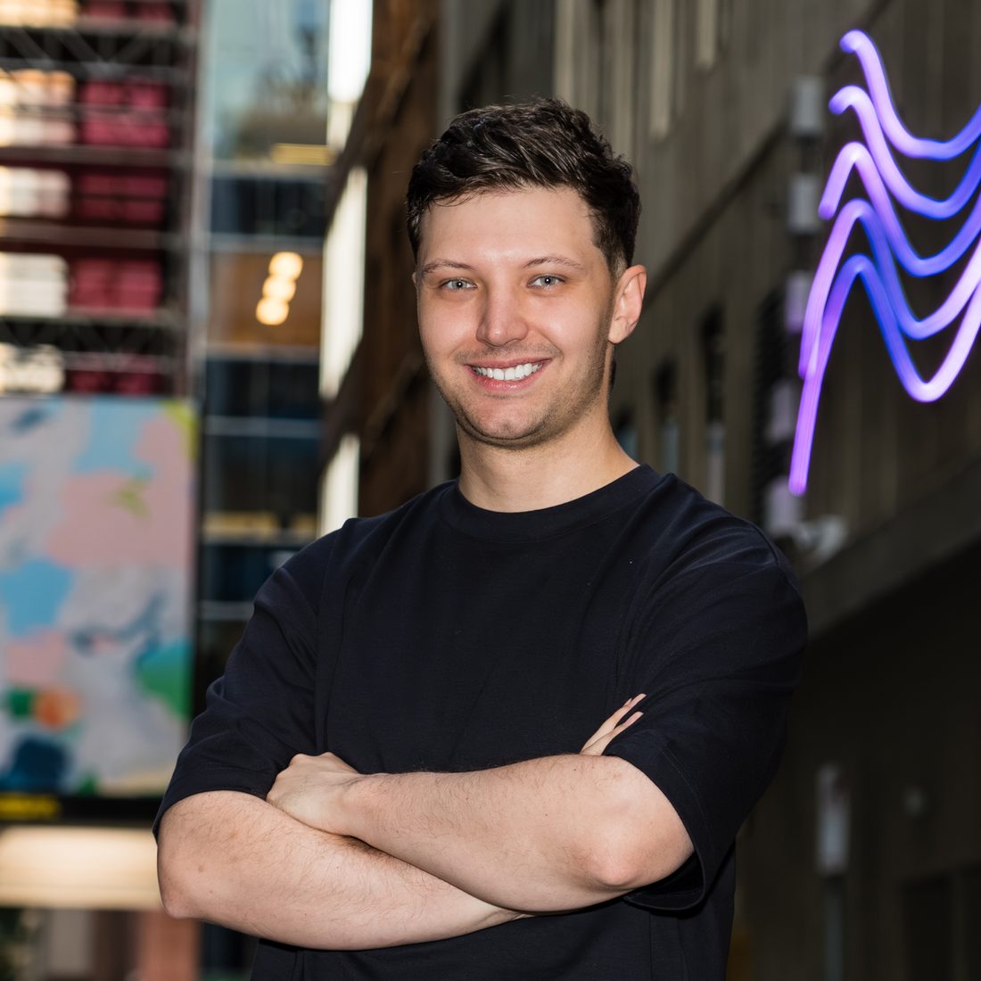 Portrait beside a neon wave sculpture